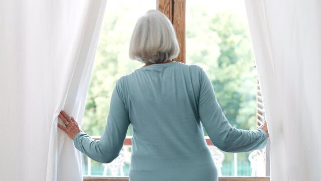 Open curtains, back and window with senior woman, morning, view and wake up with sunrise, home and fresh air. Pensioner, apartment or elderly lady in living room, sunlight and start a new day