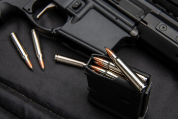 Close-up of .223 carbine cartridges. Loaded weapon clip. Weapons in the back
