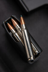 Naklejka premium Close-up of .223 carbine cartridges. Loaded weapon clip. Weapons in the back