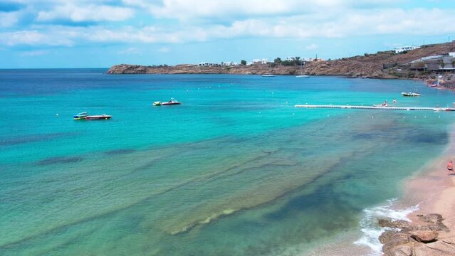Paraside Beach in Mykonos, Greece, umbrella and luxury beach chairs beds in front of blue ocean. Most famous beach with crystal water and beach music bars. Gimbal cinematic ProRes graded from Log