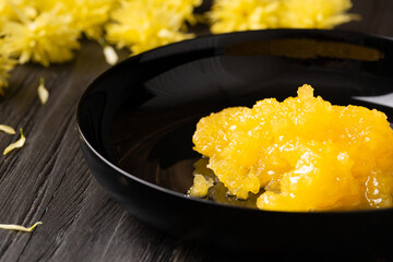 Crystallized honey in a plate on a dark background