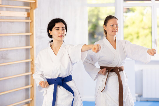 Women in kimono standing in fight stance during group karate training