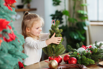 Little girl playing in kitchen with Christmas tree and New Years decor. Christmas, New Year and...