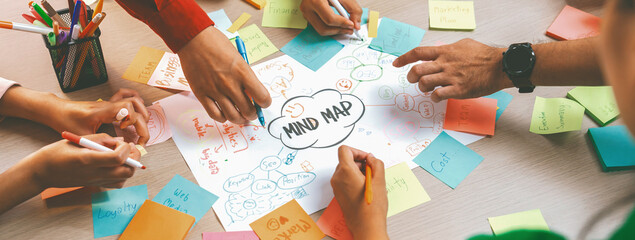 Professional startup group share creative marketing idea by using mind map. Young skilled business people brainstorm business plan while writing sticky notes. Focus on hand. Closeup. Variegated. - Powered by Adobe