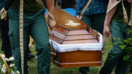 Burial. Men lower the coffin into the grave. - obrazy, fototapety, plakaty