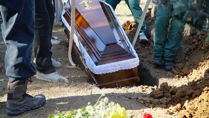 Burial. Men lower the coffin into the grave.