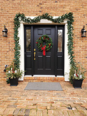 front door to a brick house with Christmas wreath and a lantern at the entrance.