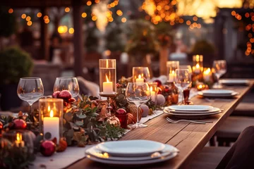 Fotobehang Christmas outdoor dinner table setting with garland and candles at night, winter holiday season, tablescape © Sunshower Shots