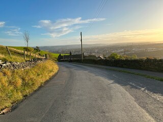 Autumn sunset over, Bradford Old Road, with fields, dry stone walls, and haze near, Halifax, UK
