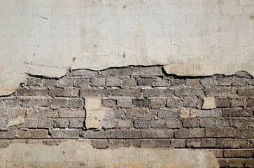 gray brick wall covered with gray cement with a break in the cement