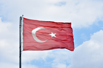 Turkish flag flapping under cloudy blue sky