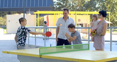 Unplugged Entertainment: Family is playing outdoor table tennis, active and healthy lifestyle while...