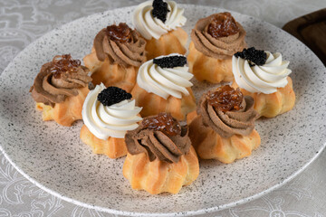 Festive savory profiteroles with caviar, cream cheese and dill and liver pate. An appetizer for Christmas and New Year's Eve.