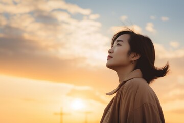 Asian woman looking up at sunset sky