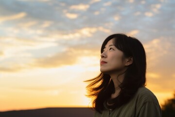 Asian woman looking up at sunset sky