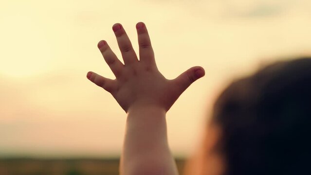 Hand of kid in sun close-up, Silhouette. Kid palm pull to sun. Religion lends help hand. Kid Prayer in religion. Hand happy person sunset. Child stretches hand to sun. Concept faith religion prayer