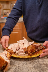 Thanksgiving dinner. Man staying in kitchen holding plate with roasted turkey. Getting ready for traditional dinner.