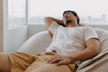 Asian man rest and relaxed on bean bag sofa in the apartment on weekends.