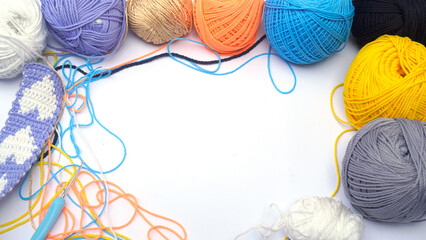 Colorful knitting yarn balls and embroidery accessories on white wooden textured table background....