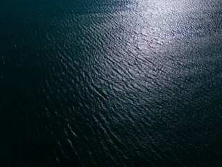 An aerial view of a majestic expanse of blue sea with lapping waves, the bright glint of the sun...