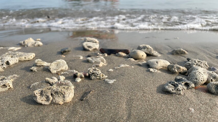 Sandy beach and white coral pebbles among the foam of the waves