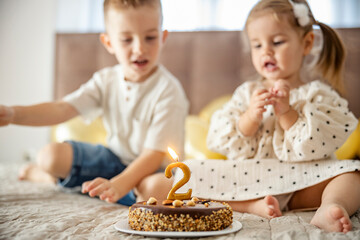 Obraz na płótnie Canvas A birthday cake with big two candle with children celebrating birthday.