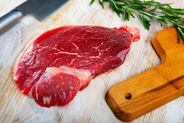 Fresh raw beef steak on wooden background with herbs