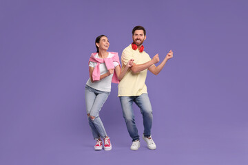 Happy couple dancing together on violet background