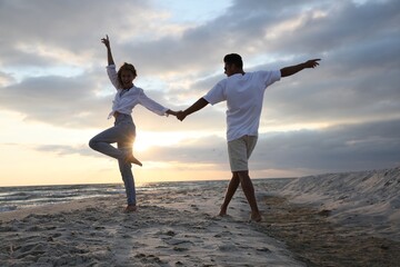Fototapeta premium Happy couple dancing on beach at sunset