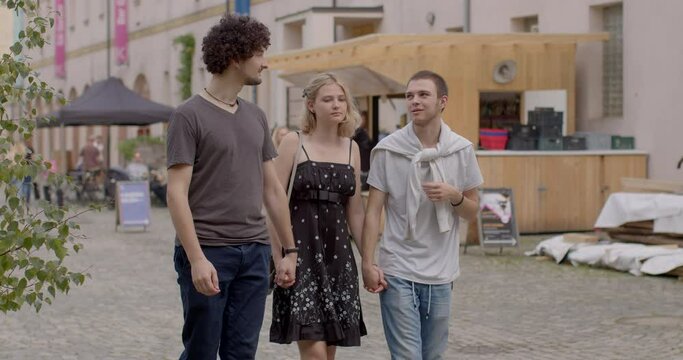 Girl and two guys walking talking. Romantic relationships among three individuals, involve consensually and openly loving, connecting with multiple partners simultaneously. People lifestyle