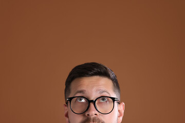 Man in stylish glasses on brown background, closeup