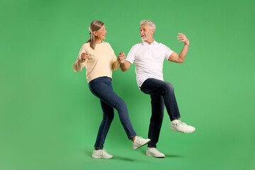 Senior couple dancing together on green background