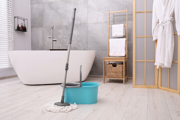 Mop and plastic bucket in bathroom. Cleaning floor - obrazy, fototapety, plakaty