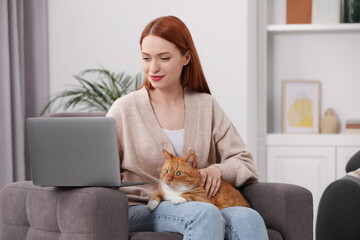 Woman with cat working in armchair at home