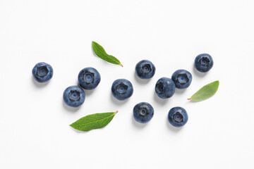 Tasty fresh blueberries with green leaves on white background, flat lay