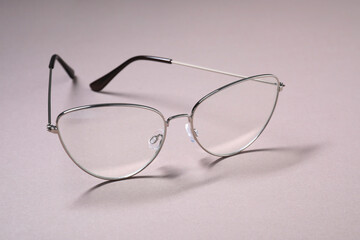 Stylish pair of glasses with metal frame on light background, closeup