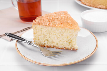 Piece of tasty sponge cake on white tiled table