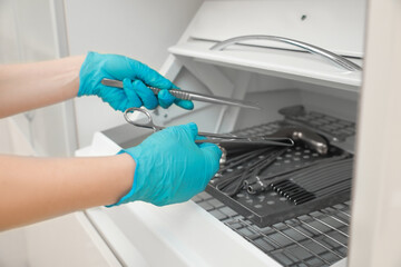 Gynecologist putting medical instruments into sterile storage chamber in clinic, closeup