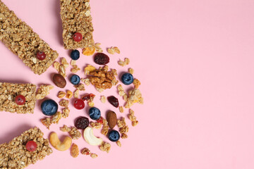 Tasty granola bars and ingredients on pink background, flat lay. Space for text