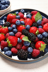 Different fresh ripe berries on light wooden table, closeup