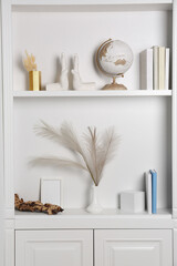 White shelves with books, globe and different decor indoors. Interior design
