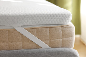 White memory foam mattress topper on grey bed, closeup