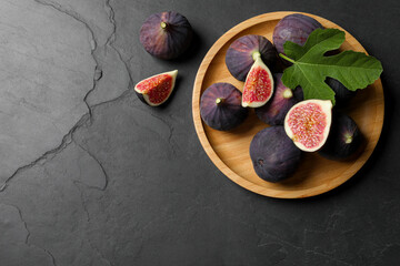 Obraz na płótnie Canvas Plate with fresh ripe figs and green leaf on black table, flat lay. Space for text
