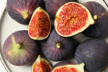 Plate with whole and cut ripe figs on table, top view