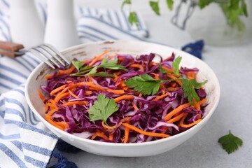 Tasty salad with red cabbage in bowl on light grey table, closeup