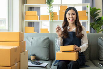 Small business entrepreneur or freelance Asian woman working with parcel boxes Young successful...