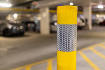 Yellow parking garage pole - close up - cars in background