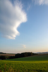 夕陽が当たる緑の牧草畑と空に浮かぶ雲
