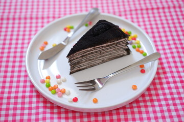 Piece of homemade chocolate crepes cake on a white plate