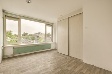 an empty room with wood flooring and large windows looking out onto the street in front of the apartment building